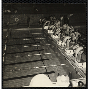 Six swimmers prepare to dive off the starting blocks at a Boys' Club swimming championship. A caption on the back of the photograph states "Ready to go"