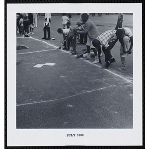 A line of boys put on their shoes during a game on Tom Sawyer Day