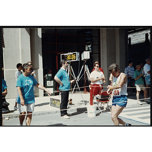 A man checks his watch after crossing the finish line during the Battle of Bunker Hill Road Race