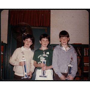 Three Boys' Club members posing with their basketball tournament trophies