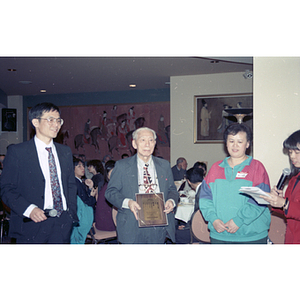 Elderly man holds award plaque