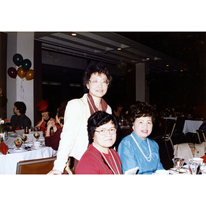 Chinese Progressive Association director Suzanne Lee (standing) with two women at the Rainbow Leadership Award Ceremony and Dinner at Boston University