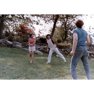Young man gets ready to catch an unidentified object, while another young man and a woman watch