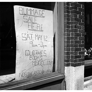Rummage sale sign hanging in a store front window