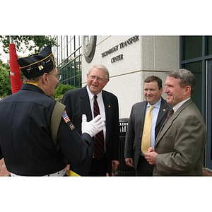 A man in uniform speaks to other men in front of Egan Research Center at the Veterans Memorial groundbreaking