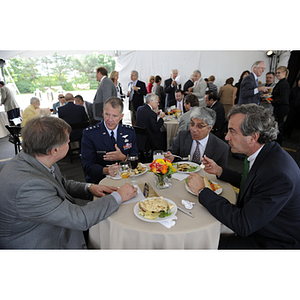 Four men sit eating at the reception for the groundbreaking of the George J. Kostas Research Institute for Homeland Security