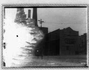 View of wooden buildings with smokestacks in the upper left