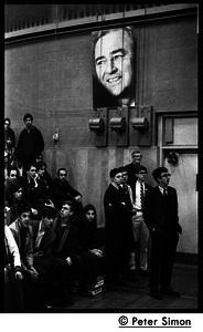 Audience awaiting speech by presidential candidate Eugene McCarthy at Boston University, standing under large poster for McCarthy