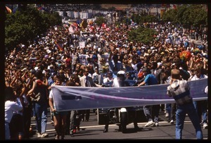 Massive crowd marching in the San Francisco Pride Parade, carrying banner reading 'Mayors contingent': Art Agnos waving to the crowd from the back of an automobile