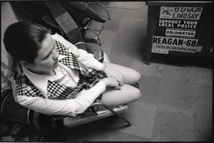 Young Americans for Freedom (YAF) office: YAF member seated in front of cabinet adorned with bumper stickers for Reagan, Goldwater, the police, and opposing SDS