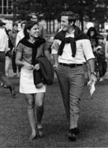 A male and female student walk to a football game, 1969