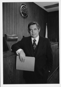 Suffolk University President David J. Sargent (1989-2010) standing in moot court room, leaning on wooden railing