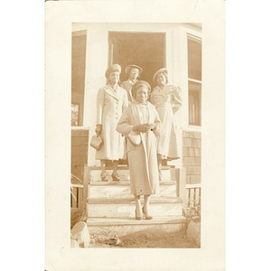 Four women in coats posing on steps