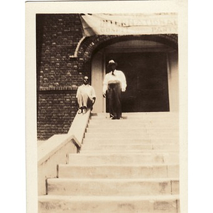 Two men pose on steps under a banner