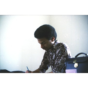 Young Hispanic man, seated and writing, at a program at La Alianza Hispana, Boston.