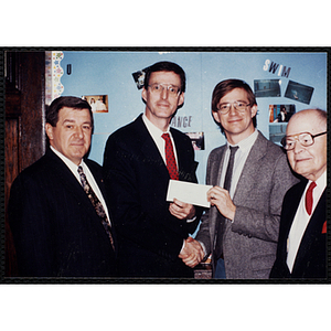 Charlestown Clubhouse Director Jerry Steimel, standing third from left, accepts a check from an unidentified group of men and shakes hands