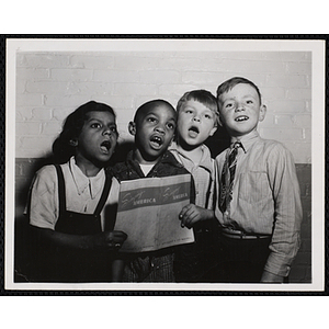 A girl and three boys from the Boys' Clubs of Boston sing together while holding a song book titled "Singing America"