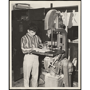 A boy using a bandsaw for his woodworking project at the South Boston Boys' Club