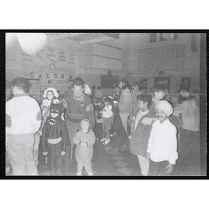 Two children in Halloween costumes pose with a man as two other boys look on