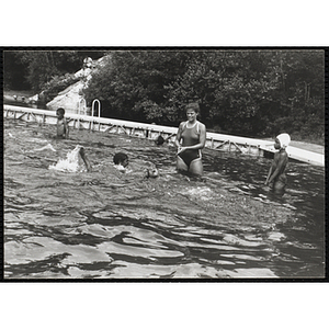 A group of children swim near a supervisor