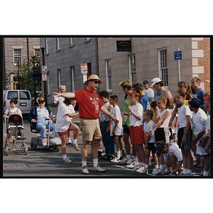 A man addresses a group of children at the start line of the Bunker Hill Road Race