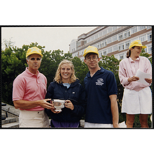 Executive Director Jerry Steimel (right), a woman, and a man pose with a silver bowl during the Battle of Bunker Hill Road Race