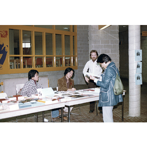 Woman reads a brochure from an information booth at an indoor event during the Dragon Boat Festival