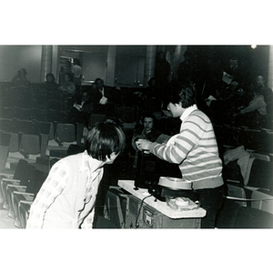 Man adjusts the slide projector and equipment in the Josiah Quincy School auditorium for an event regarding the normalization of U.S. and China relations