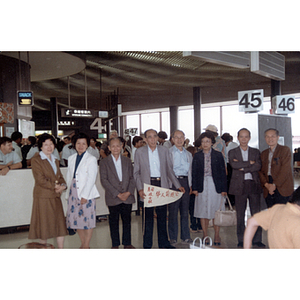 Men and women stand in a line in a Chinese public transportation building