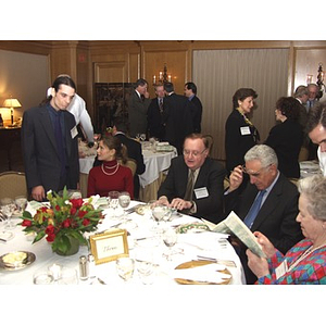 Guests looking at menu at gala dinner to honor John Hatsopoulos, second from right