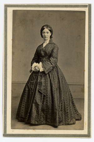 Full-length portrait of Edna Dean Proctor, governess, standing, facing front, location unknown