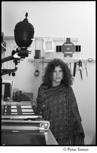 Usha (Cathy Brown) standing next to an enlarger in a darkroom