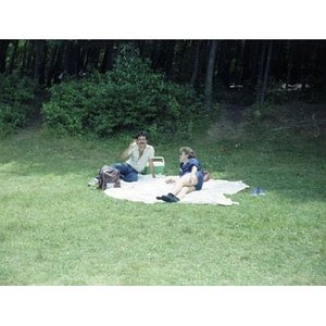 Two Hispanic American men sit on a blanket at a La Alianza Hispana staff picnic