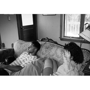 Unidentified young Inquilinos Boricuas en Acción employees lounge on a couch in someone's living room.