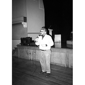 Man at the microphone at the front of the hall of the Jorge Hernandez Cultural Center.