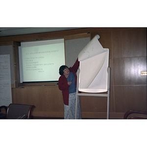 One of the moderators at a board training session flips over a page of the flip chart.