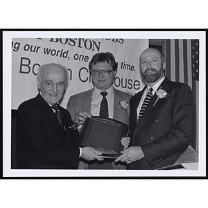 Ed Hoell, at right, and an unidentified man present a plaque at a St. Patrick's Day Luncheon