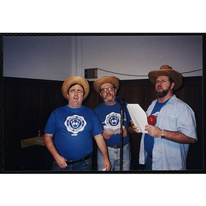 Three Bunker Hillbilly alumni sing into a microphone at a reunion event