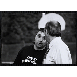 Two men talk at a Chelsea Housing Authority Basketball League game