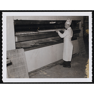 A member of the Tom Pappas Chefs' Club works with bread loaves in an industrial oven