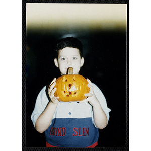 A boy holds a carved pumpkin