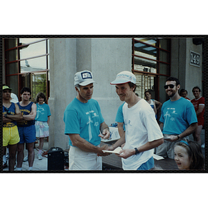 A man receives a certificate from another man as he shakes his hand at the Battle of Bunker Hill Road Race