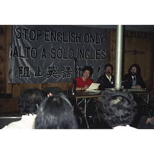 Speakers address an audience member at a meeting with the Anglo-American, Hispanic, and Chinese communities to discuss bilingual education