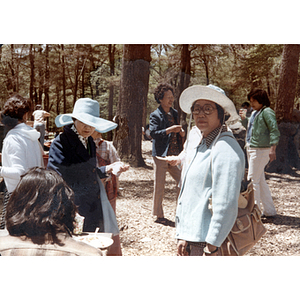 Woman stands with others in a wooded picnic area