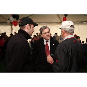 President Freeland talks to two people under the tent before the Homecoming game