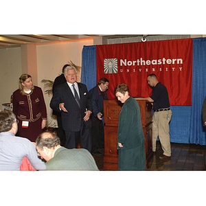 Senator Kennedy speaks to audience members in front of the podium during preparations for the press conference on student financial aid cuts