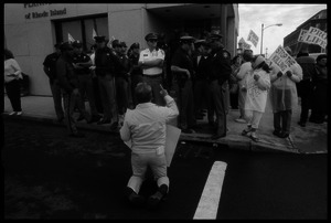 Pro-life protester on his knees, facing a line of police in front of the Providence Planned Parenthood clinic