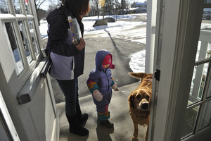 Mother and child leaving the New Salem Public Library, greeted by a waiting golden retriever