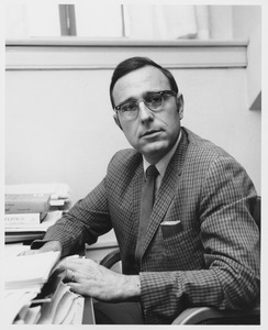 Theodore William Leed sitting indoors, working behind desk