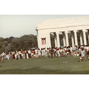 People gather around a columned building at an outdoor event